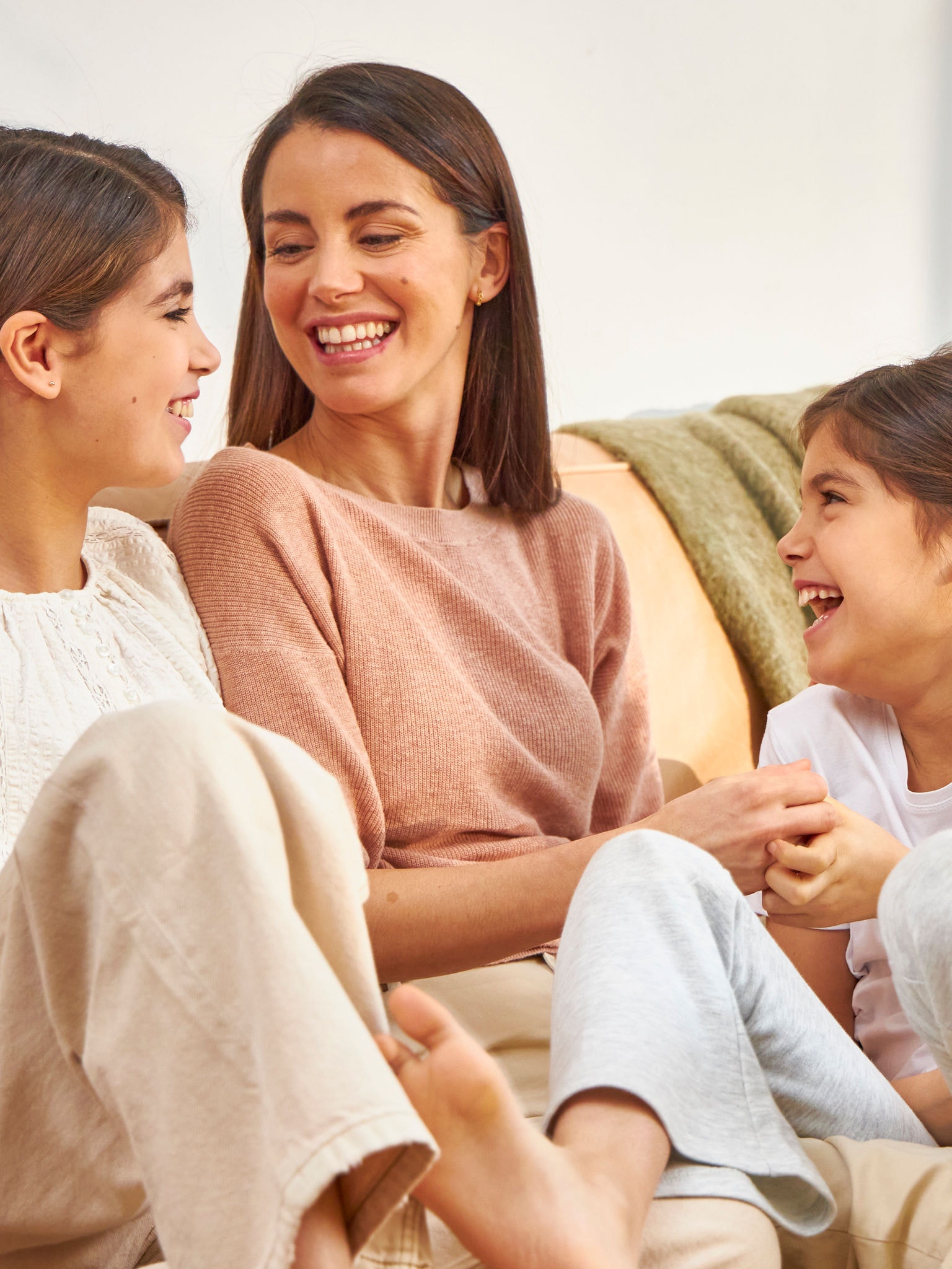 Mère et ses deux filles riant sur le canapé