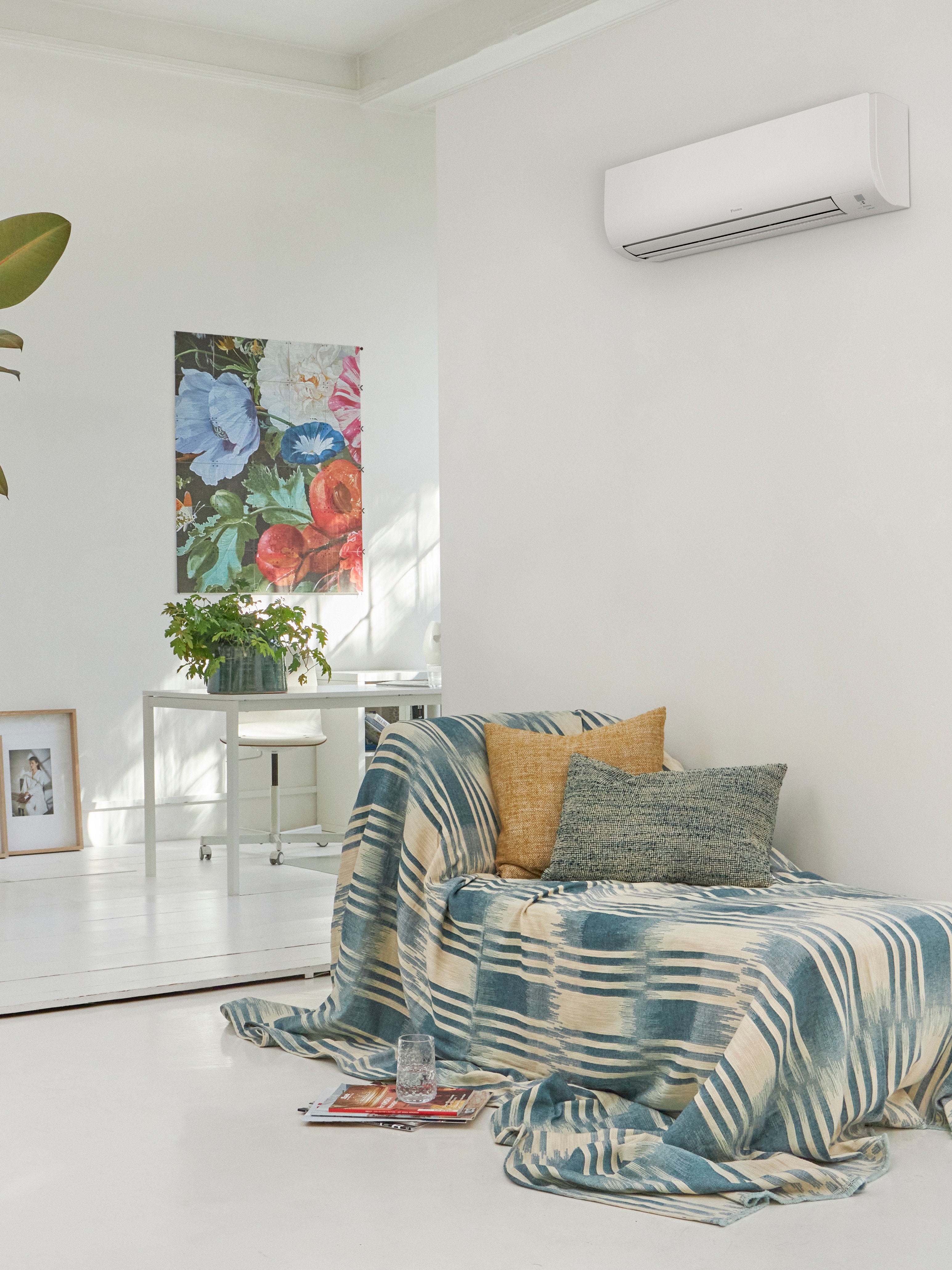 Salon blanc avec un canapé et solution climatique murale au-dessus.