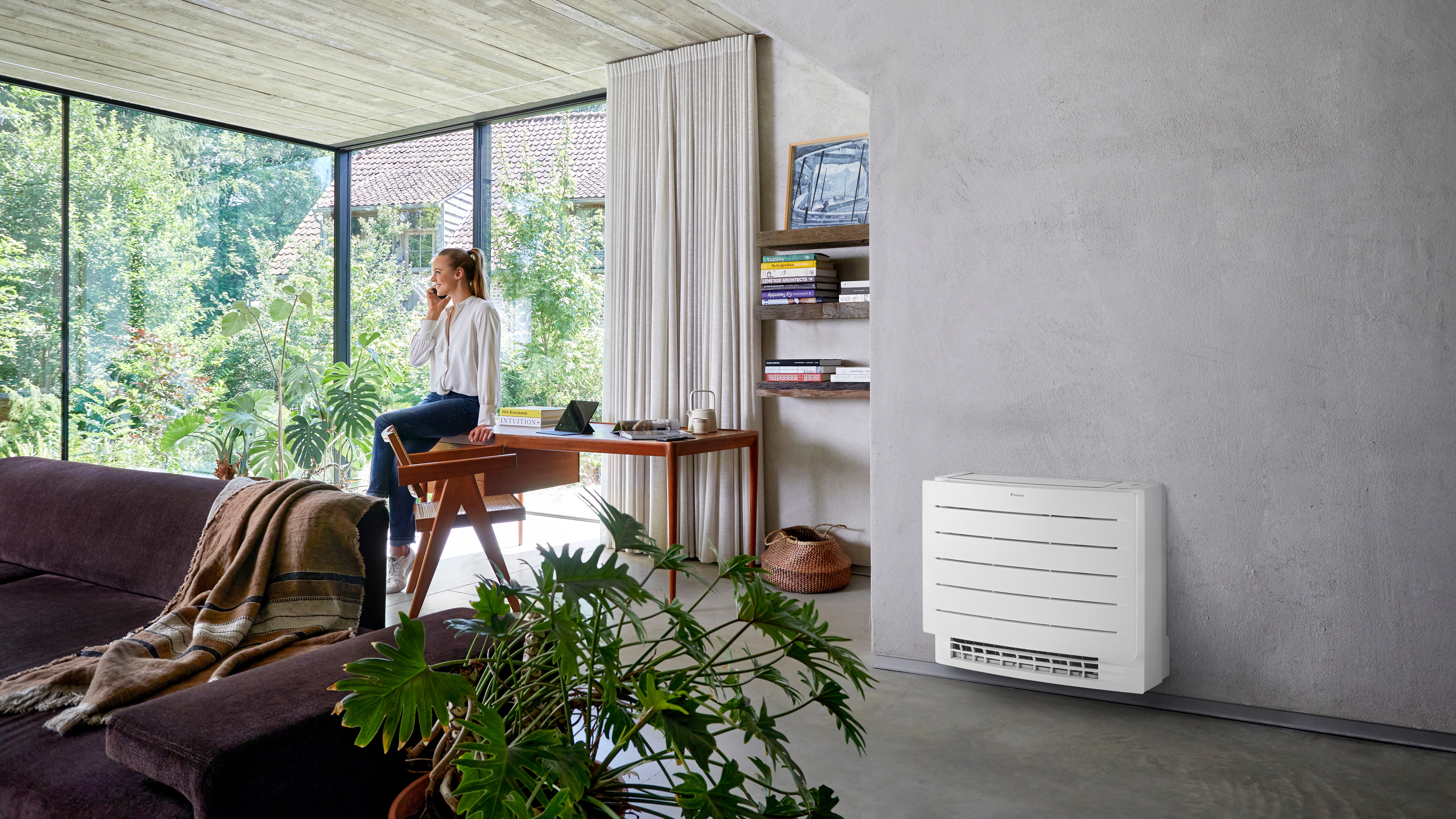 Vrouw aan de telefoon, genietend van een comfortabel klimaat in haar woonkamer met een vloermodel