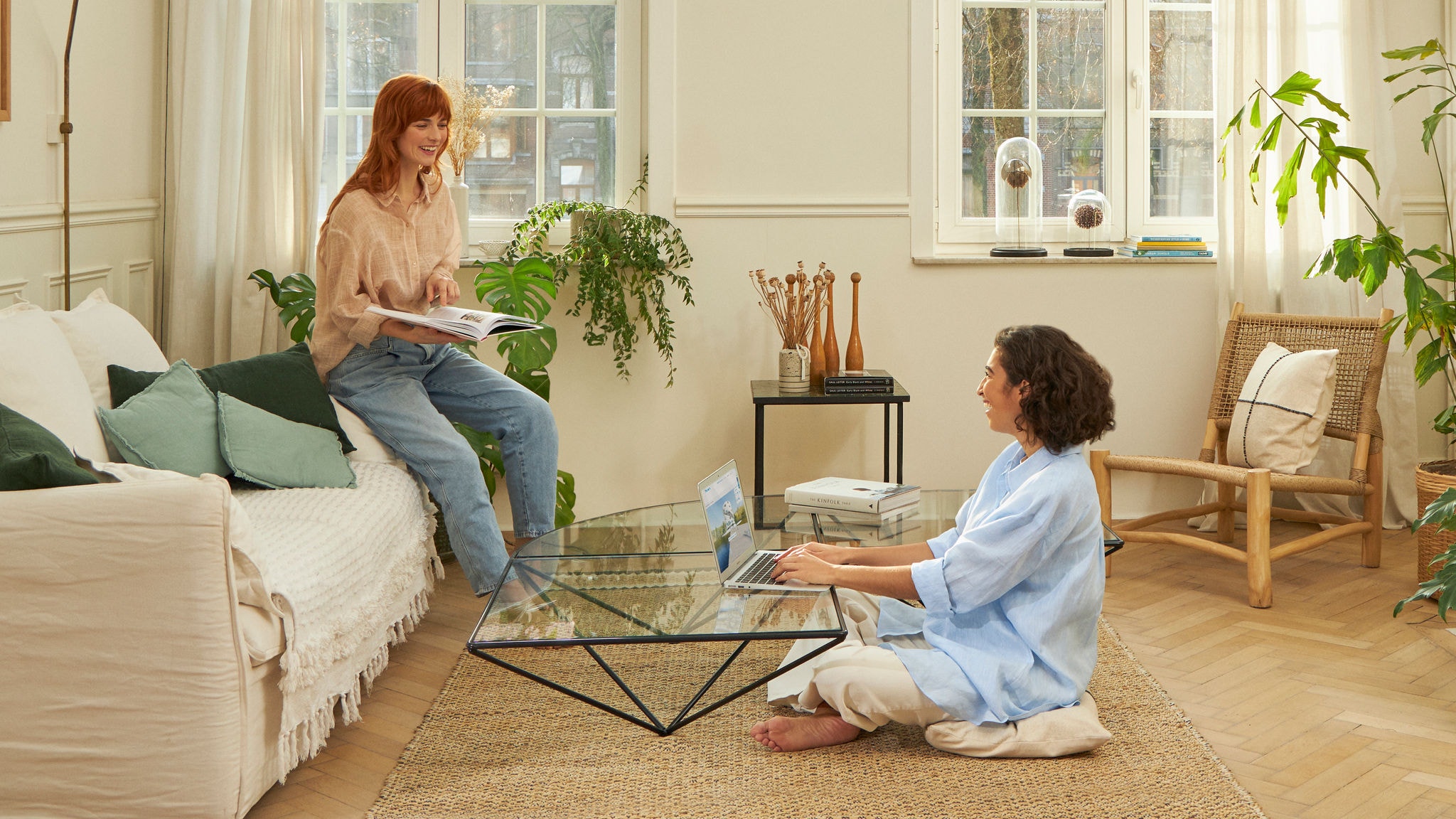Twee vrouwen lachen in de woonkamer terwijl ze werken en lezen