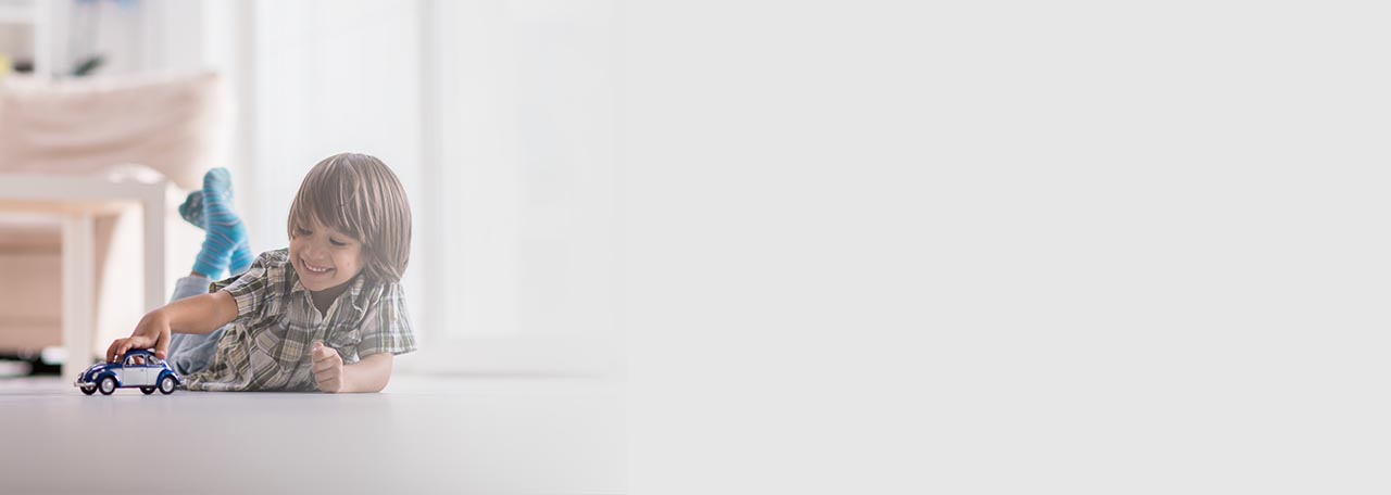 Jongen speelt met een speelgoedauto op de vloer.